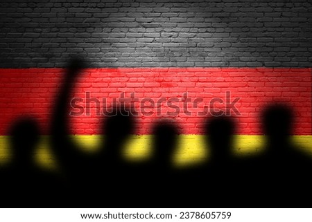 The refugees migrate to Germany . Silhouette of illegal immigrants . Europe union migration policy. Germany flag painted on a brick wall with protesters