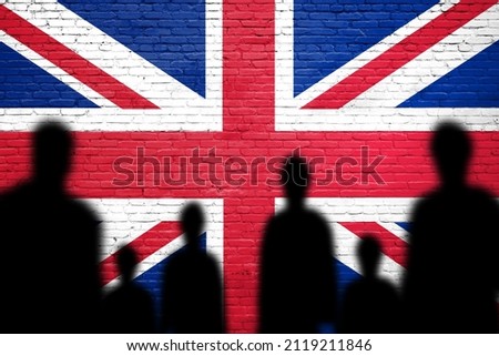 The refugees migrate to UK. Silhouette of illegal immigrants . United Kingdom migration policy. United Kingdom flag painted on a brick wall