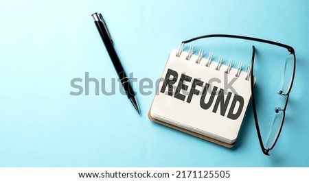 REFUND text written on notepad on the blue background