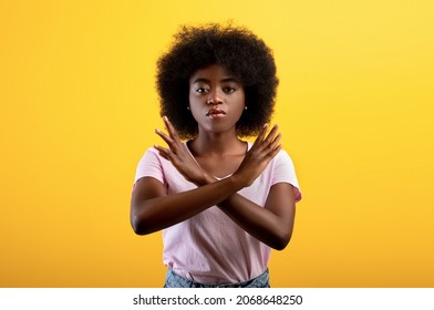 Refusal concept. Upset black lady showing stop gesture with crossed hands, refusing something unwanted while standing over yellow studio background - Shutterstock ID 2068648250