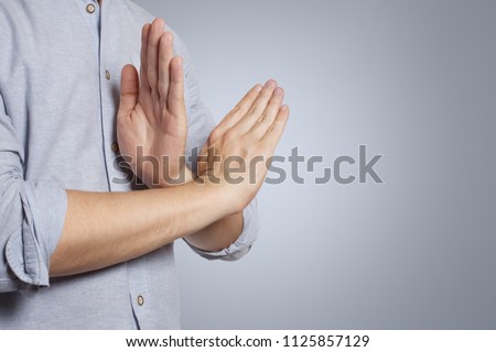 Refusal gesture, crossed hands on grey background