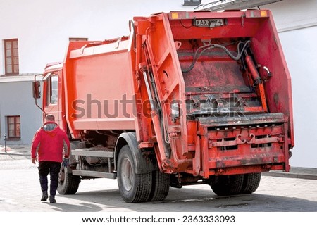 Refuse collector work on rear load garbage truck in the city. Garbage removal work in residential district. Worker and garbage truck
