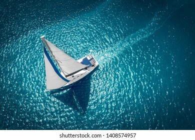 Regatta sailing ship yachts with white sails at opened sea. Aerial view of sailboat in windy condition. - Shutterstock ID 1408574957