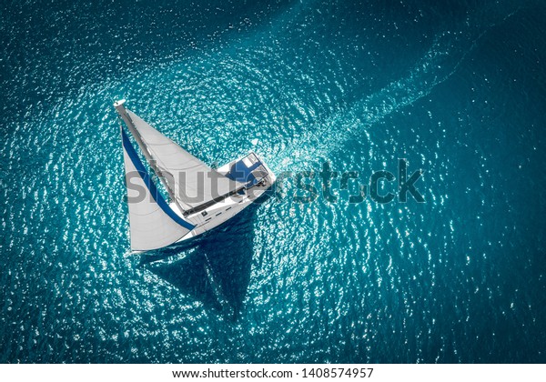 Regatta sailing ship yachts with white sails at opened sea. Aerial view of sailboat in windy condition.