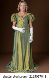 A Regency Woman Wearing A Green Shot Silk Gown And White Gloves And Standing Against A Studio Backdrop