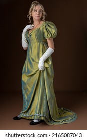 A Regency Woman Wearing A Green Shot Silk Gown And White Gloves And Standing Against A Studio Backdrop