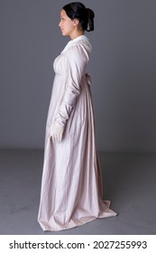 A Regency Woman Wearing A Pink Cotton Dress Against A Grey Studio Backdrop