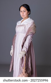 A Regency Woman Wearing A Pink Cotton Dress Against A Grey Studio Backdrop