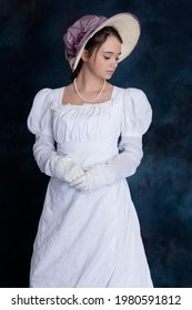 A Regency woman wearing a white muslin dress and bonnet and looking to the side