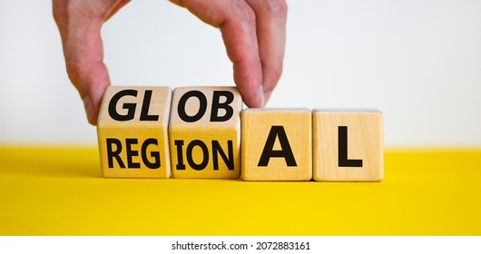 Regional or global symbol. Businessman turns wooden cubes and changes the word 'regional' to 'global'. Beautiful yellow table, white background. Business and regional or global concept. Copy space. - Shutterstock ID 2072883161