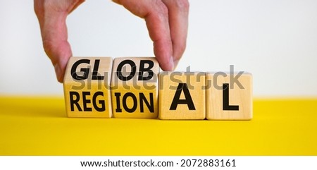Regional or global symbol. Businessman turns wooden cubes and changes the word 'regional' to 'global'. Beautiful yellow table, white background. Business and regional or global concept. Copy space.