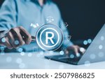 Registered trademark, intellectual property concept. Businessman working on laptop with digital icons register trademarks, copyright, patent, intellectual property law, legal protection in business.