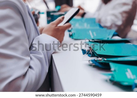 Registration desk table at conference, checking in on congress forum event, visitors and attendees register electronic ticket and receiving blue lanyard with blue name badge and entry wristband bracelet