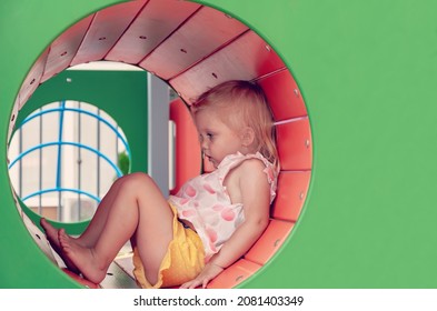 Regret Sad Little Girl Sitting Alone On The Playground At The Day Time And Feeling Excluded By The Others. Loneliness, Stressed Depressed Child Having Depression, Anxiety, Trouble Of Mental Health.