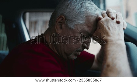 Regretful senior man feeling shame and guilt, remembering trauma from the past, struggling alone inside parked car leaning forward holding into steering wheel