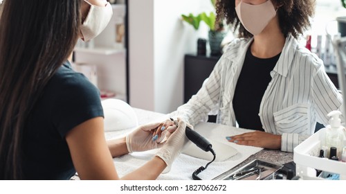 Regular Client After Opening Salon After Lockdown And Procedures. Asian Woman Master In Rubber Gloves Doing Manicure With Electric Nail Device For African American Woman In Modern Studio, Panorama