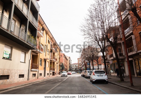 Regular italian city street\
view with cars and people walking outdoors. Alba, Italy - February\
2020