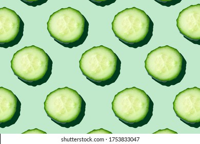 Regular seamless pattern of cucumber slices on a  pastel mint background.Photo collage,hard light, shadow,pop art design. Food blog, vegetable background. Printing on fabric, wrapping paper.Top view.