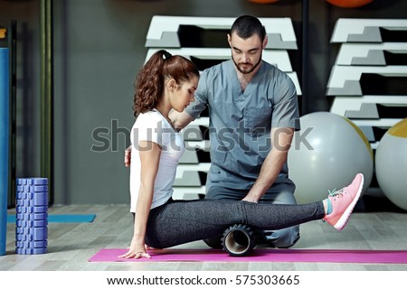 Rehabilitation concept. Young woman doing exercises under physiotherapist supervision