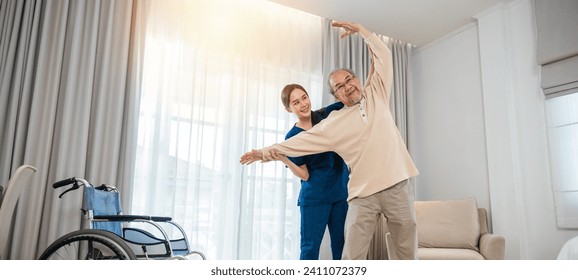 Rehabilitation of disabled people. Old senior man enjoys training with physiotherapist for outstretched arms at home, Asian physical therapist patient help elderly exercising arm stretch - Powered by Shutterstock