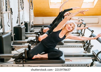 Rehabilitation, healthy lifestyle, small business concept. Sportive people making different exercise together while workout with reformer bed at modern pilates studio. - Powered by Shutterstock