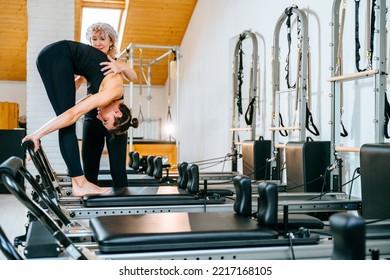 Rehabilitation, Healthy Lifestyle, Small Business Concept. Professional Mature Female Fitness Coach Teaching Girl Learn The Correctly Exercise On Pilates Reformer Bed.