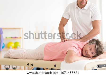 Rehabilitation of a smiling elder woman by physiotherapist at the sanatorium