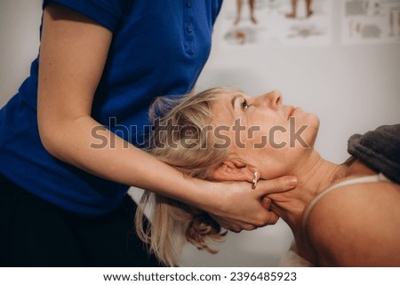 a rehabilitator massages the neck of an elderly woman