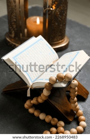Rehal with Koran and prayer beads for Ramadan on dark background, closeup