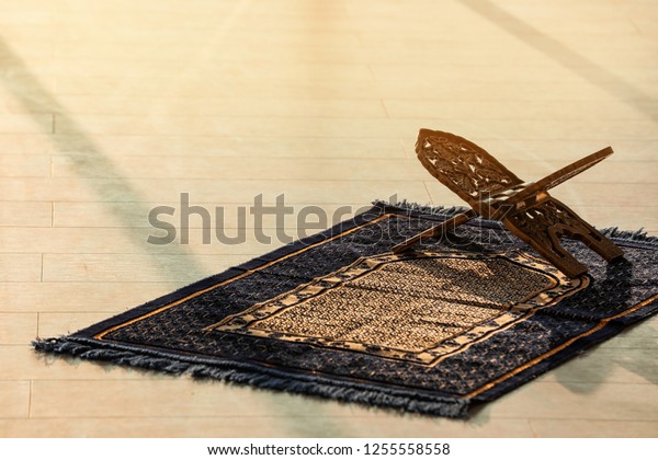Rehal on\
Muslim prayer mat indoors. Space for\
text