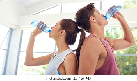 Rehydrating. Cropped shot of a young couple standing back-to-back in sportswear. - Powered by Shutterstock