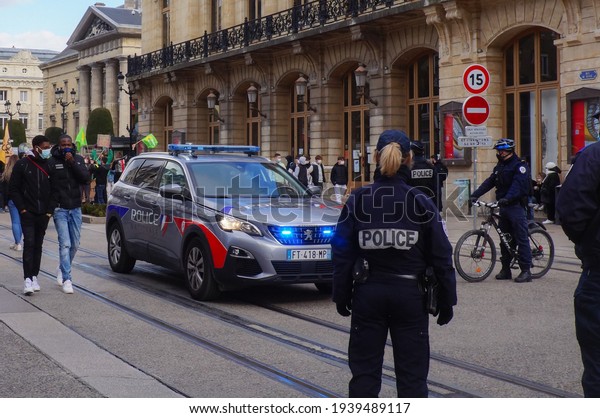 Reims, France - March 2021 - A female\
police officer and some of her colleagues by bike or on foot,\
surrounding an all-new Peugeot 5008 of the National Police, on Rue\
de Vesle during a\
demonstration