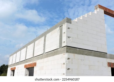 A reinforced concrete beam and reinforced concrete columns, reinforced brick lintels, a rough door and windows openings, a gable wall, walls made of aac blocks, blue sky in the background