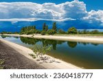 Reinforced concrete irrigation canal with storm clouds on the horizon. River Mincio in the Padan Plain or Po valley (Pianura Padana, italian). Mantua province, Italy, southern Europe.