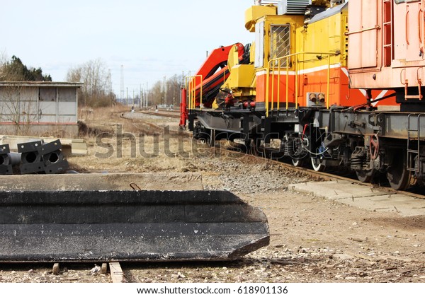 Reinforced concrete piles lie on the ground\
after unloading with a loader on the\
railway.