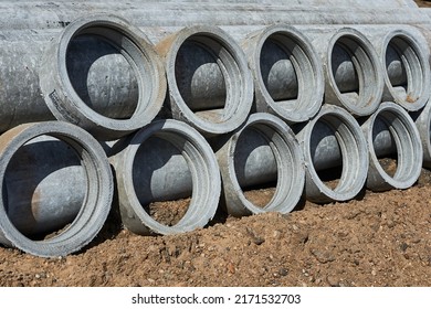 Reinforced Concrete Pipes And Connecting Rings Lie On The Sand. Sewer Repair In The City.