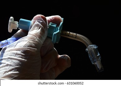 Reinforced Fenestrated Tracheostomy Cannula With Obturator In Doctor Lef Hand In Glove On Dark Background