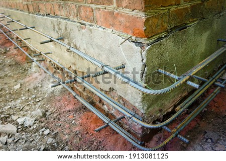 Reinforcement of base of old house for wall insulation with foam plastic. Reinforcement is connected to each other with wire for reinforcement and is fixed with metal pins at base of foundation. Foto d'archivio © 