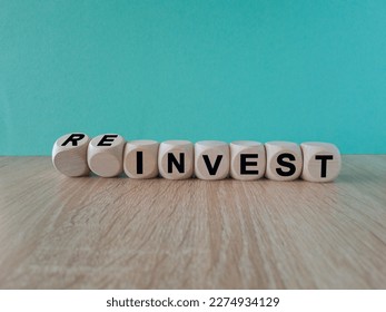 Reinvest symbol. Inverted wooden cubes with words 'invest - reinvest'. Beautiful blue background. Business and reinvest concept. Copy space.
