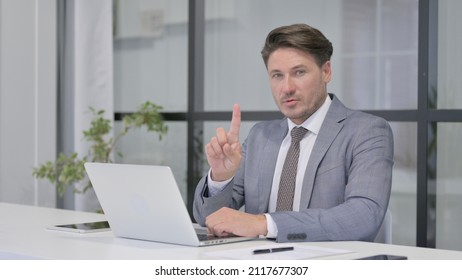 Rejecting Middle Aged Man Waving Finger While Using Laptop In Office