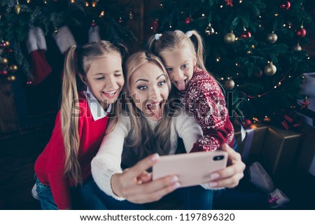 Rejoice winter december eve noel vacations. Leisure funny funky fancy positive parent mom make selfie picture show tongue out face with little small playful blonde preteen offspring soft sweater