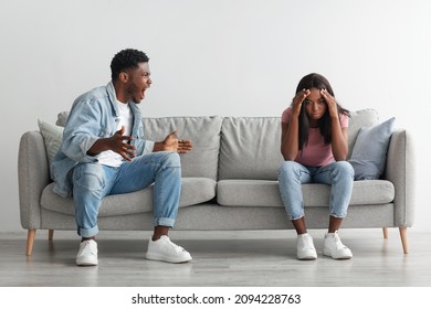 Relationship Problems Concept. Emotional Annoyed Stressed Black Couple Arguing At Home Sitting On Couch. Angry Irritated Nervous Guy Shouting At Shocked And Frustrated Gaslighted Lady, Fighting