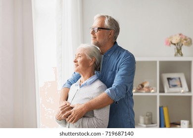 relationships, old age and people concept - happy senior couple looking through window and hugging at home - Shutterstock ID 719687140