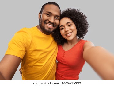 relationships and people concept - happy african american couple taking selfie over grey background - Powered by Shutterstock