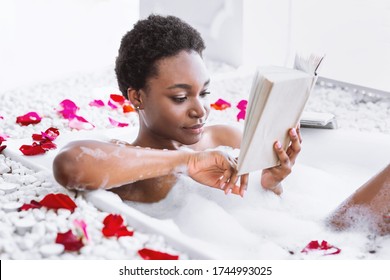 Relax in bathroom. African american girl is reading book, free space - Powered by Shutterstock