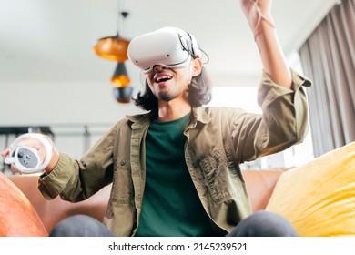 relax casual Asian adult Man Wearing Virtual Reality Headset and Holding Controllers Plays in a sport Video Game at Home. Playing VR active sport game online in the Living Room