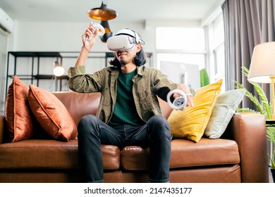 relax casual Asian adult Man Wearing Virtual Reality Headset and Holding Controllers Plays in a sport Video Game at Home. Playing VR active sport game online in the Living Room