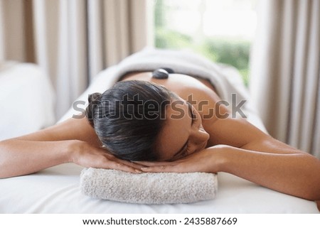 Relax, hot stone and woman at spa for massage, peace and calm for skincare at luxury resort. Beauty, therapy and person at salon with rocks on back for body treatment, health or rest for wellness