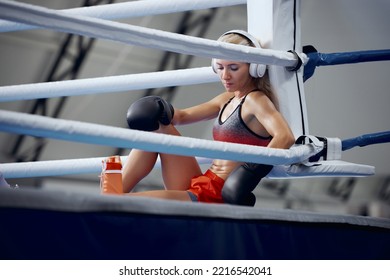 Relax music. Young female athlete, professional boxer, kickboxer have a rest after hard training at sports gym. Concept of sport, workout, active and healthy lifestyle - Powered by Shutterstock