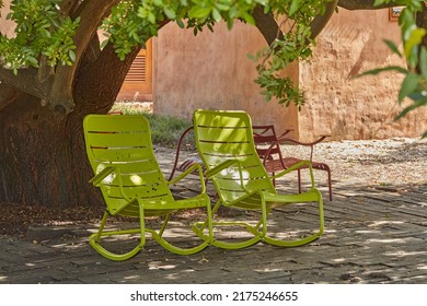 Relax On Two Green Metal Rocking Chairs Under The Shade Of A Tree In A Serene, Peaceful Private Backyard At Home On Summers Day.